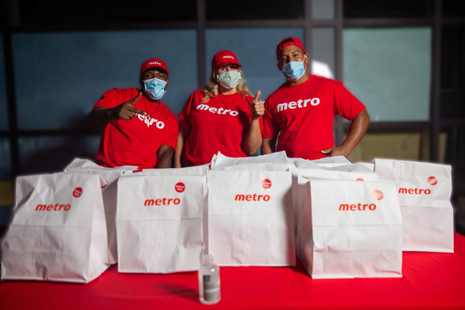 Metro Brand Ambassadors standing behind a red table with white metro paper bags