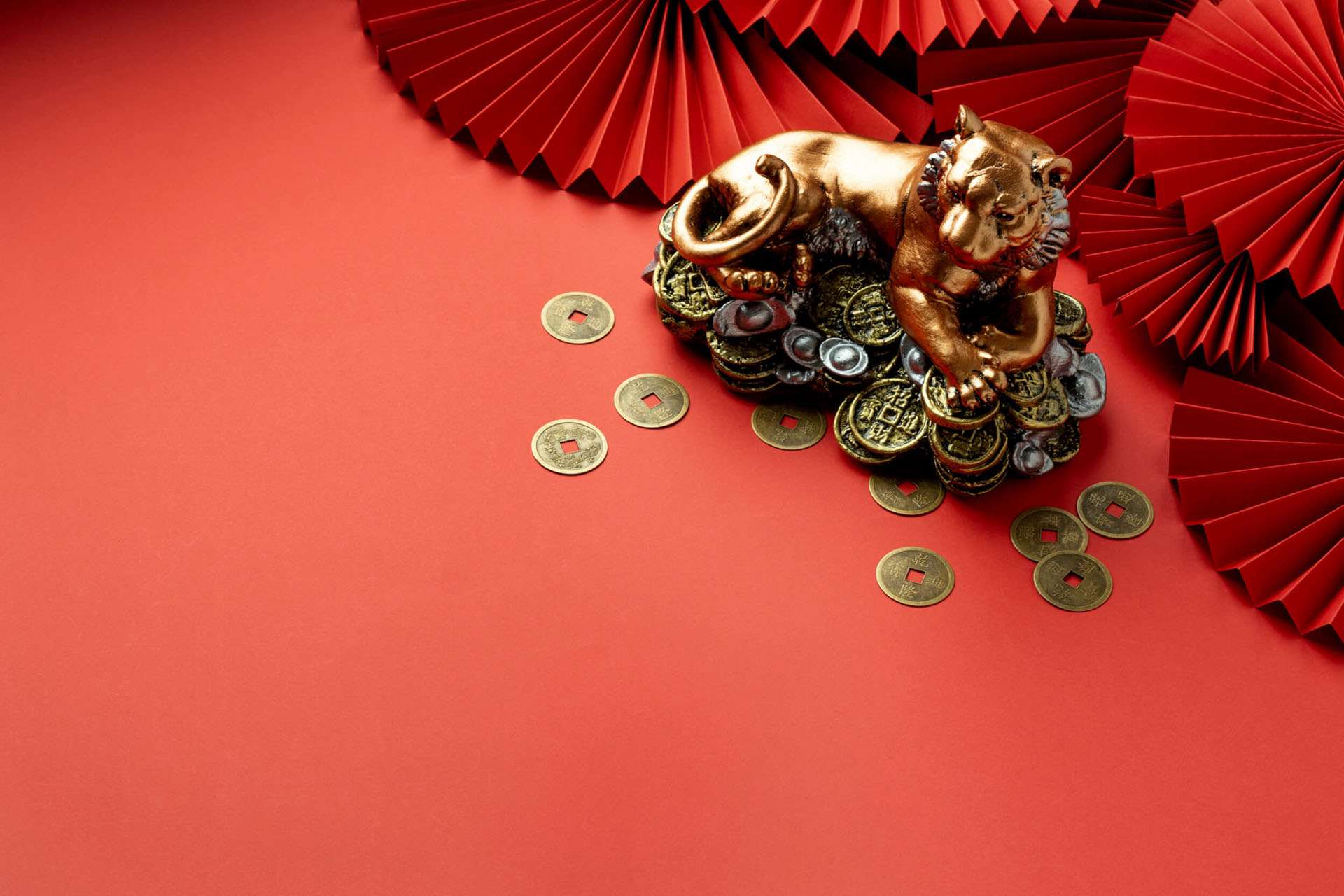 A golden tiger statue sitting on a red table with gold Chinese New year coins
