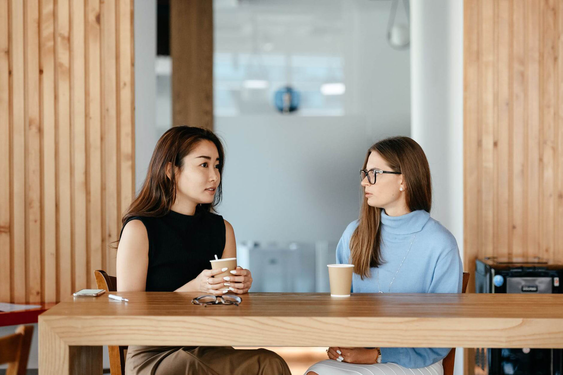 Two women sitting at a table with coffee cups