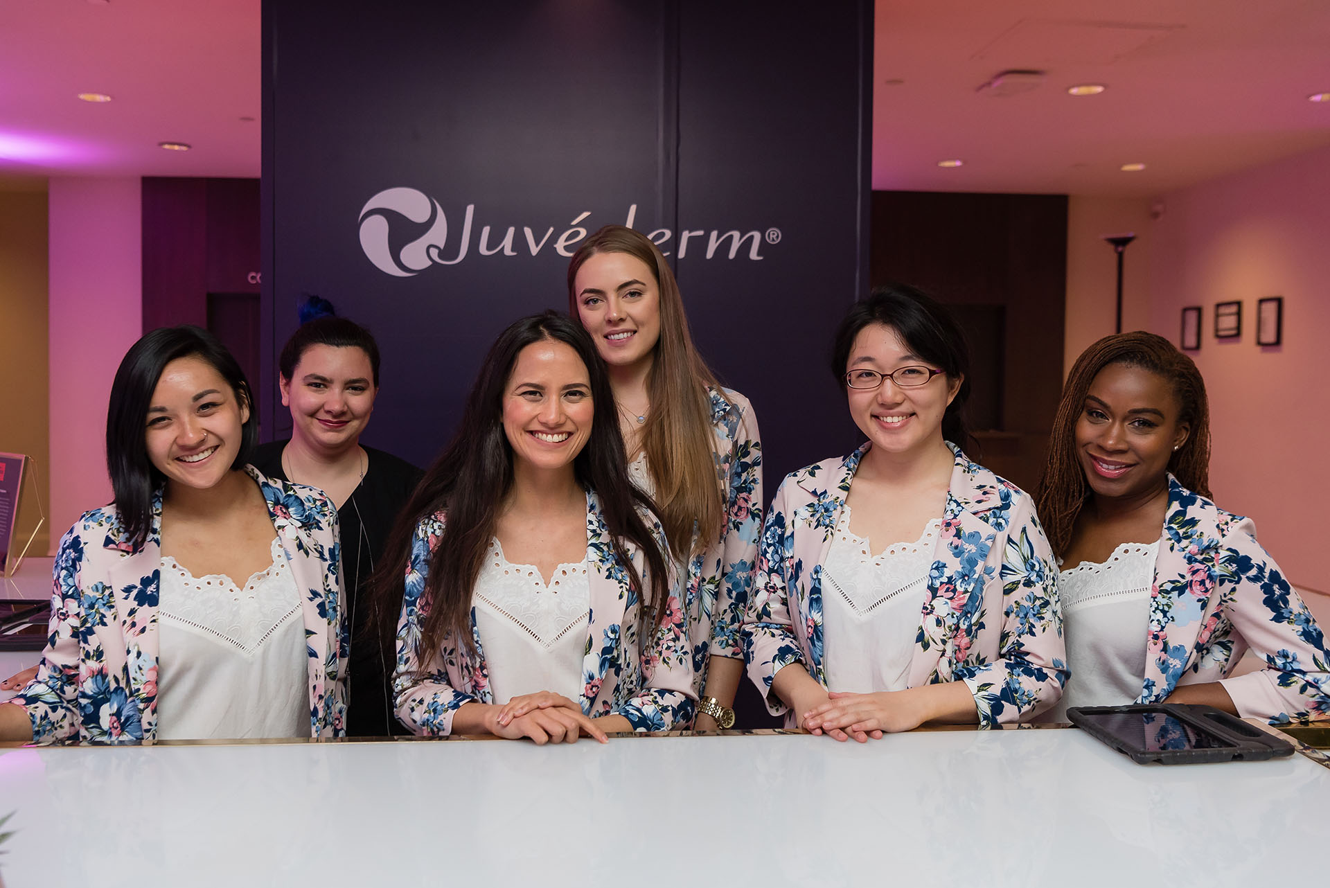 A group of women posing in floral blazers and white shirts