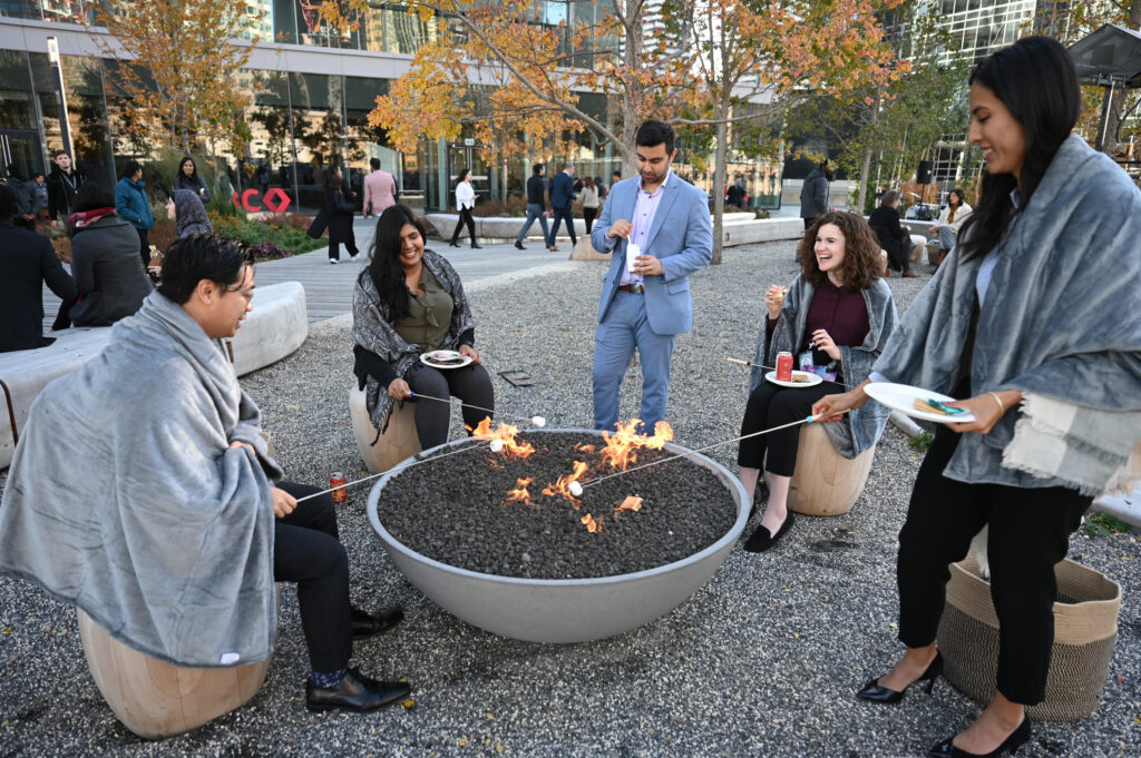 a group of people roasting marshmallows over an outdoor firepit