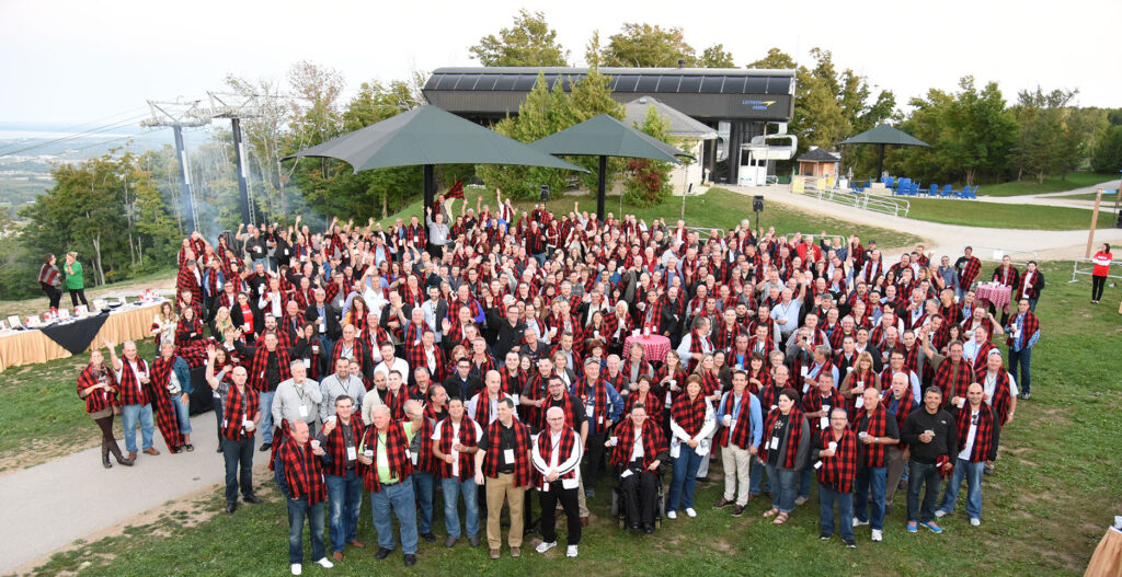 A group shot of people wearing black and red checkered scarves standing outside a ski lift