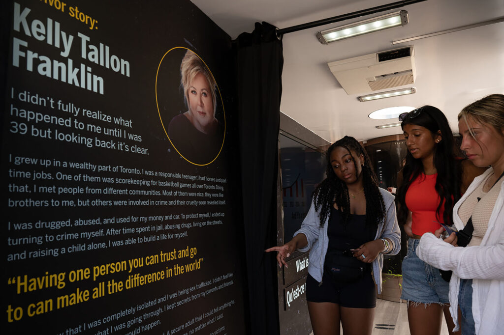 Three girls looking at a black wall with words from a survivor