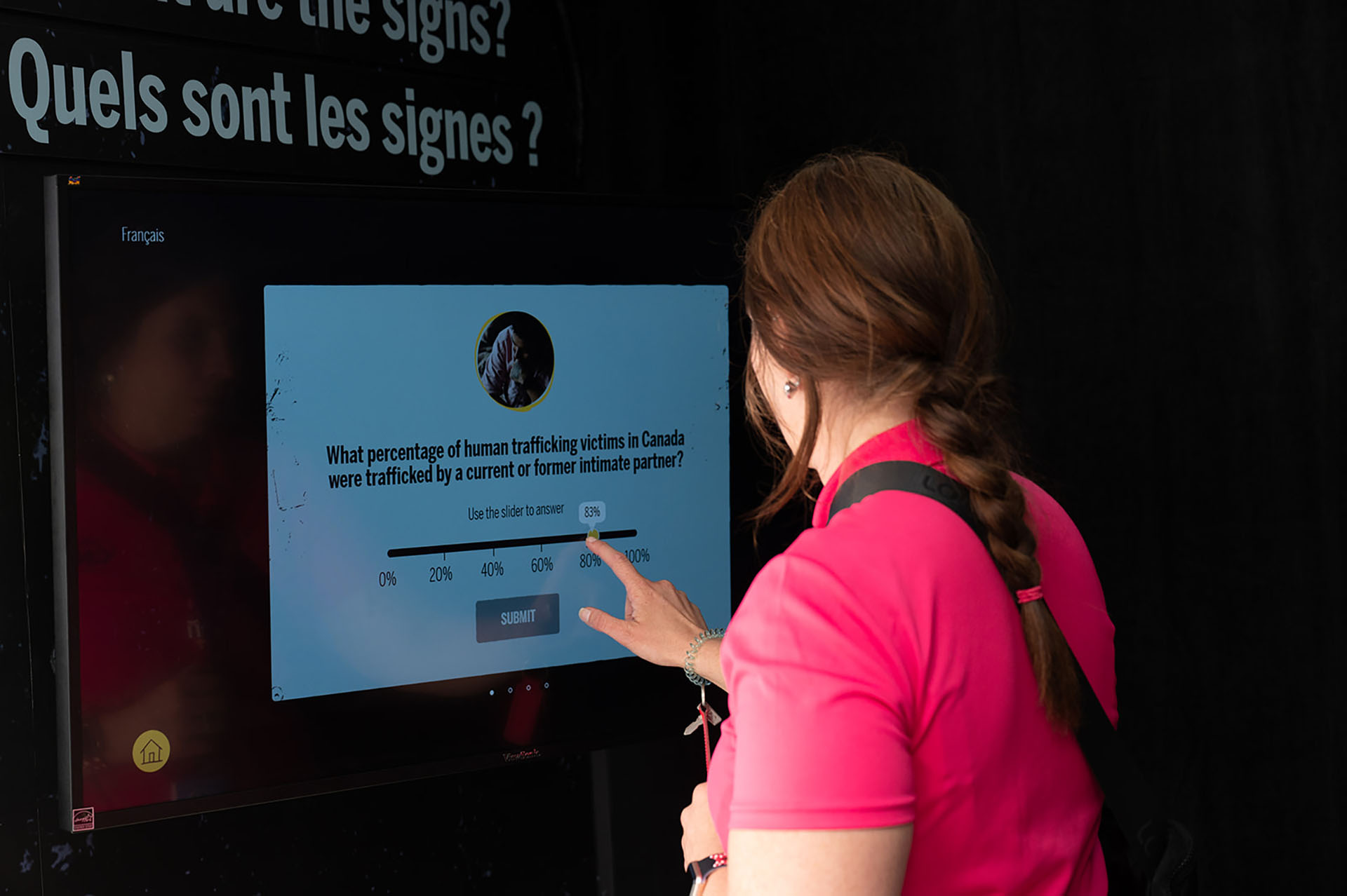A person in a red t-shirt answering a question on a touchscreen