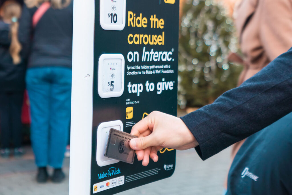 A hand holding an Amex card in front of a tap to give sign