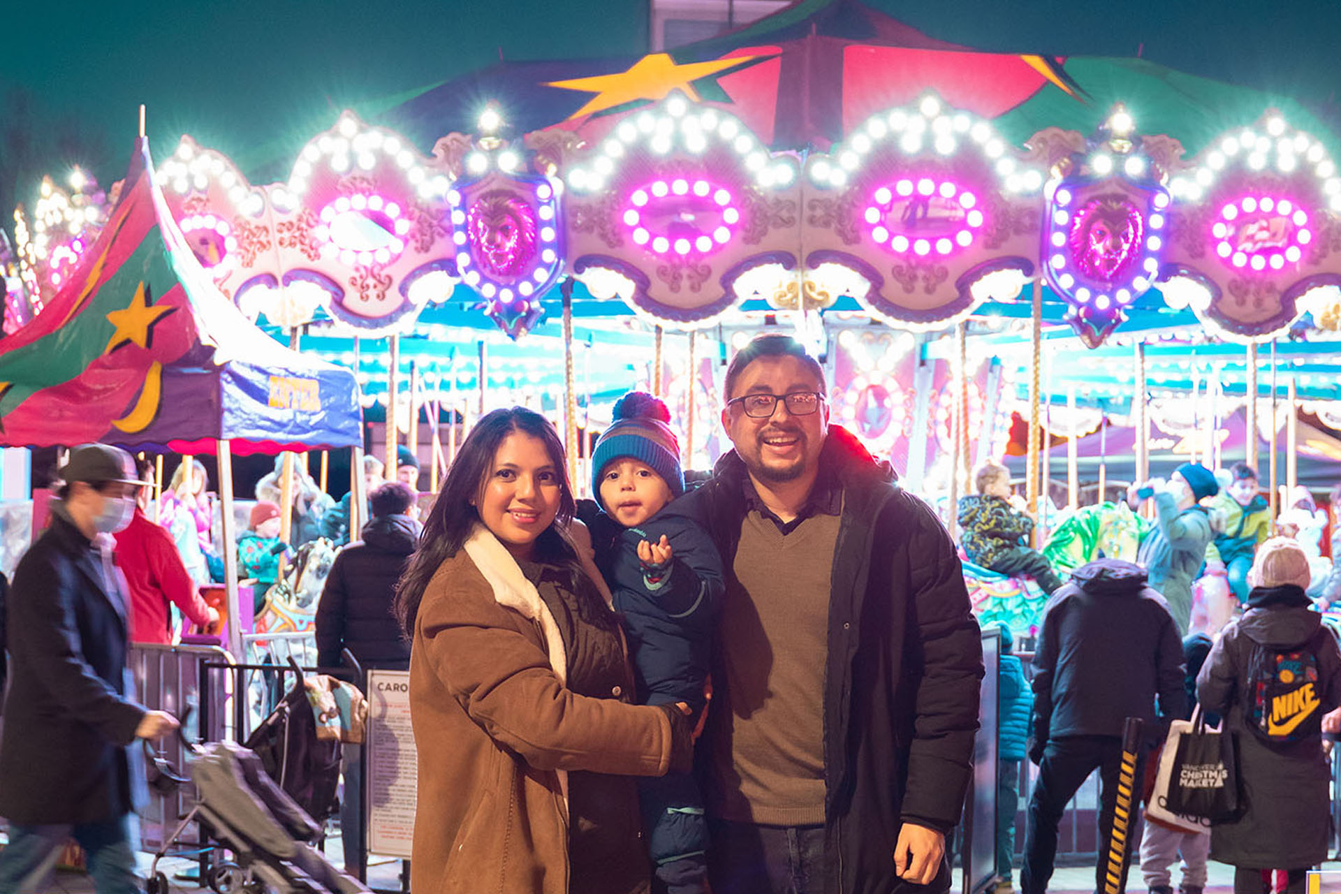 A family standing in front of a merry-go-round