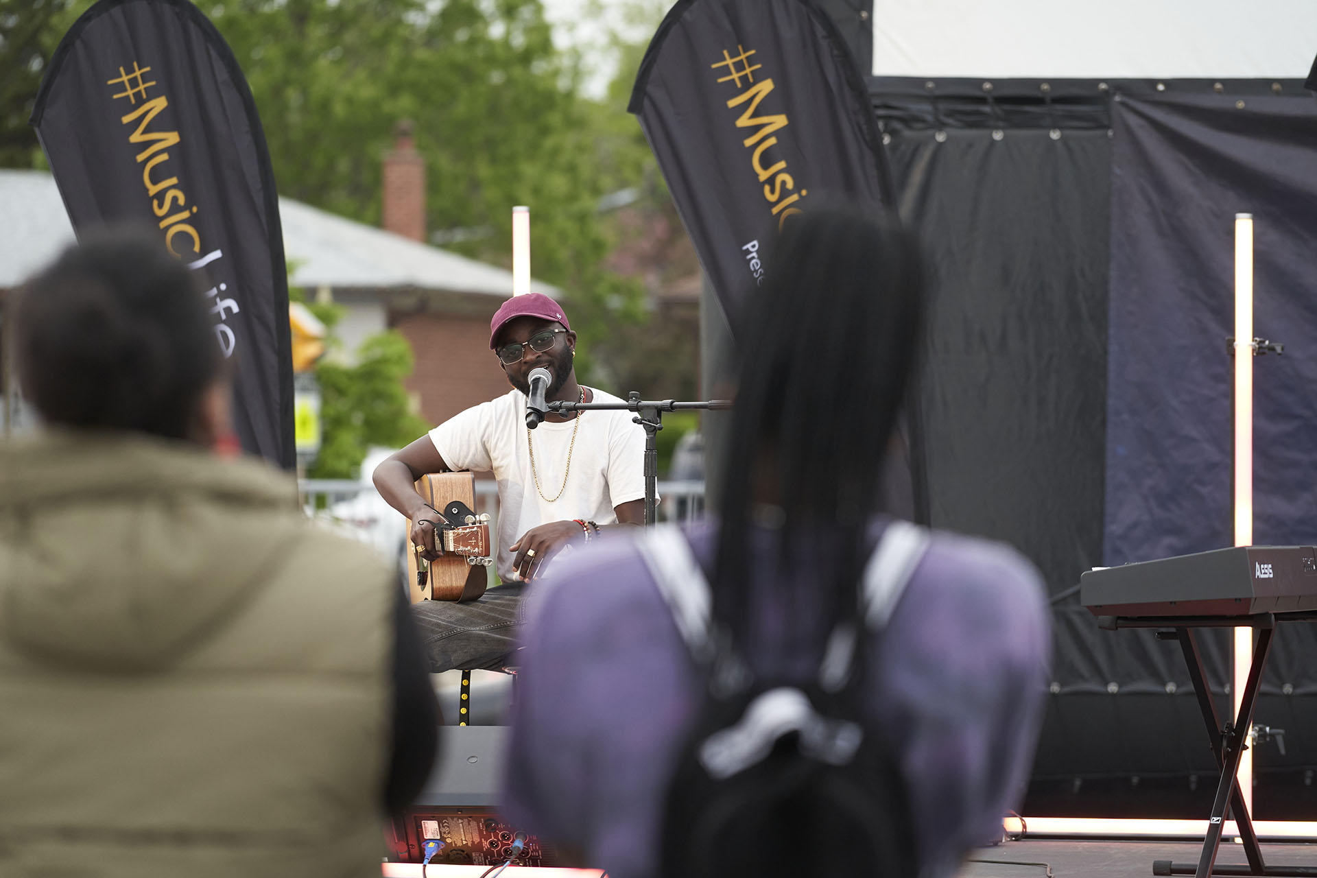 A man with a guitar performing on a stage outside.