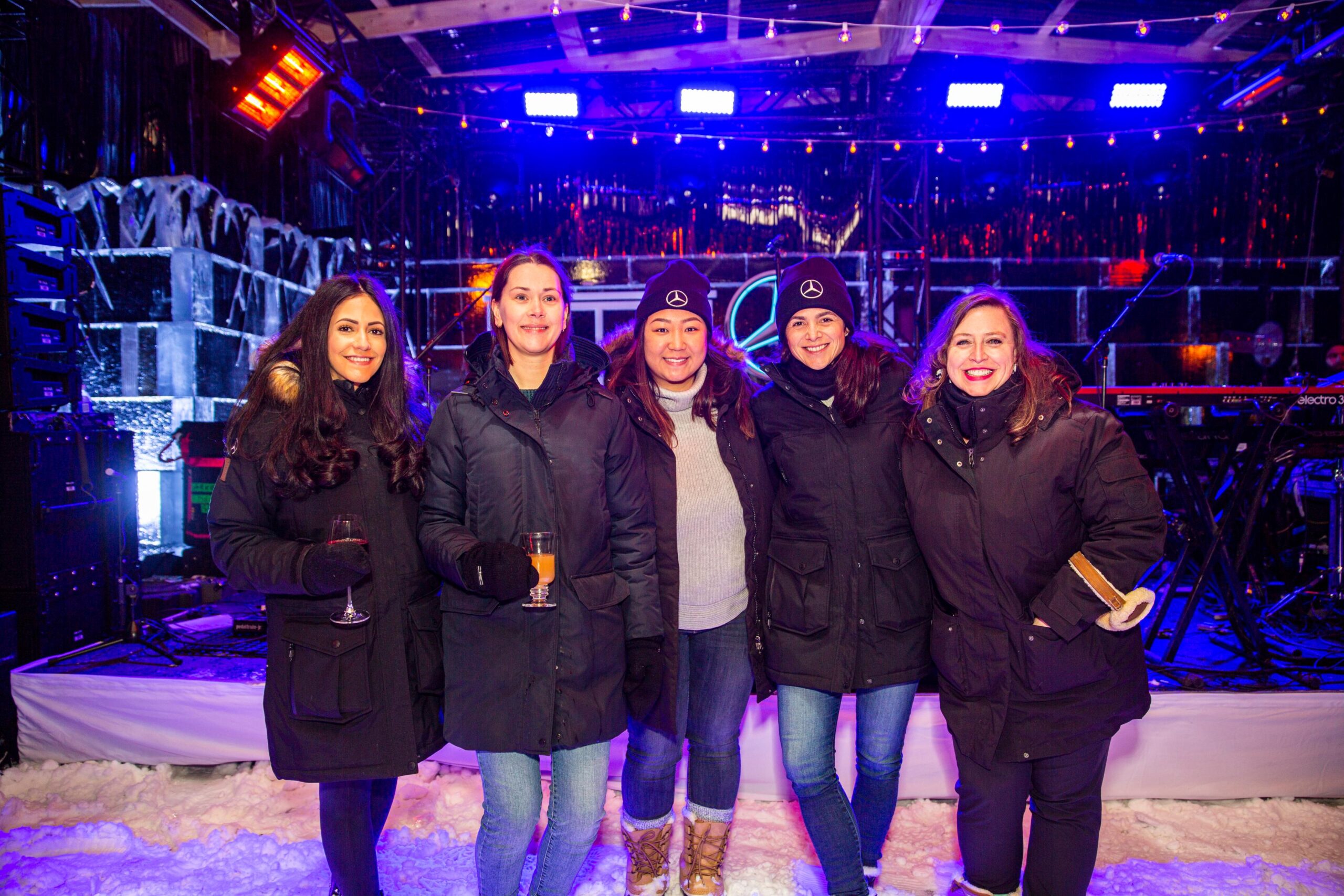 a group of women wearing winter coats in front of an ice stage