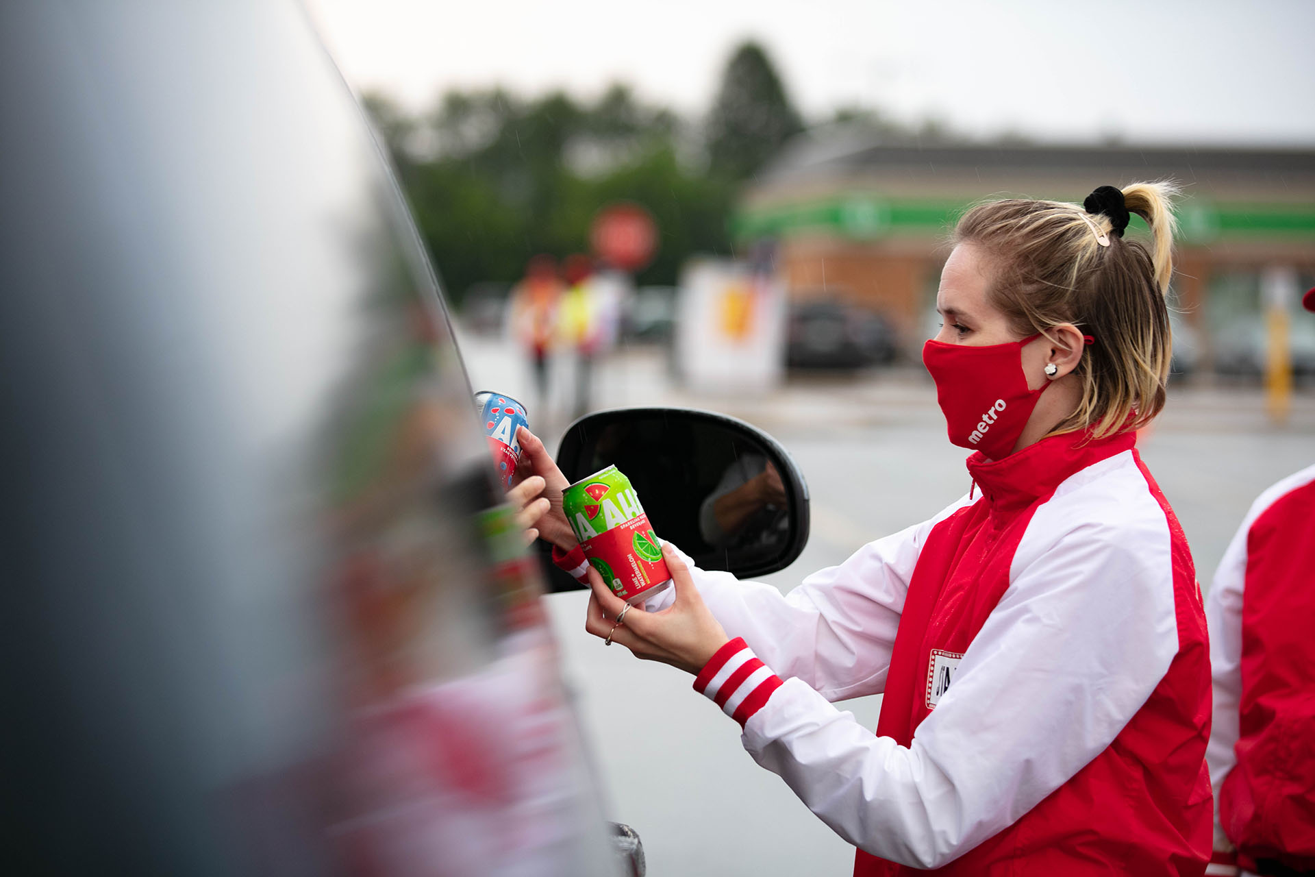 A brand ambassador handing a drink sample through a car window