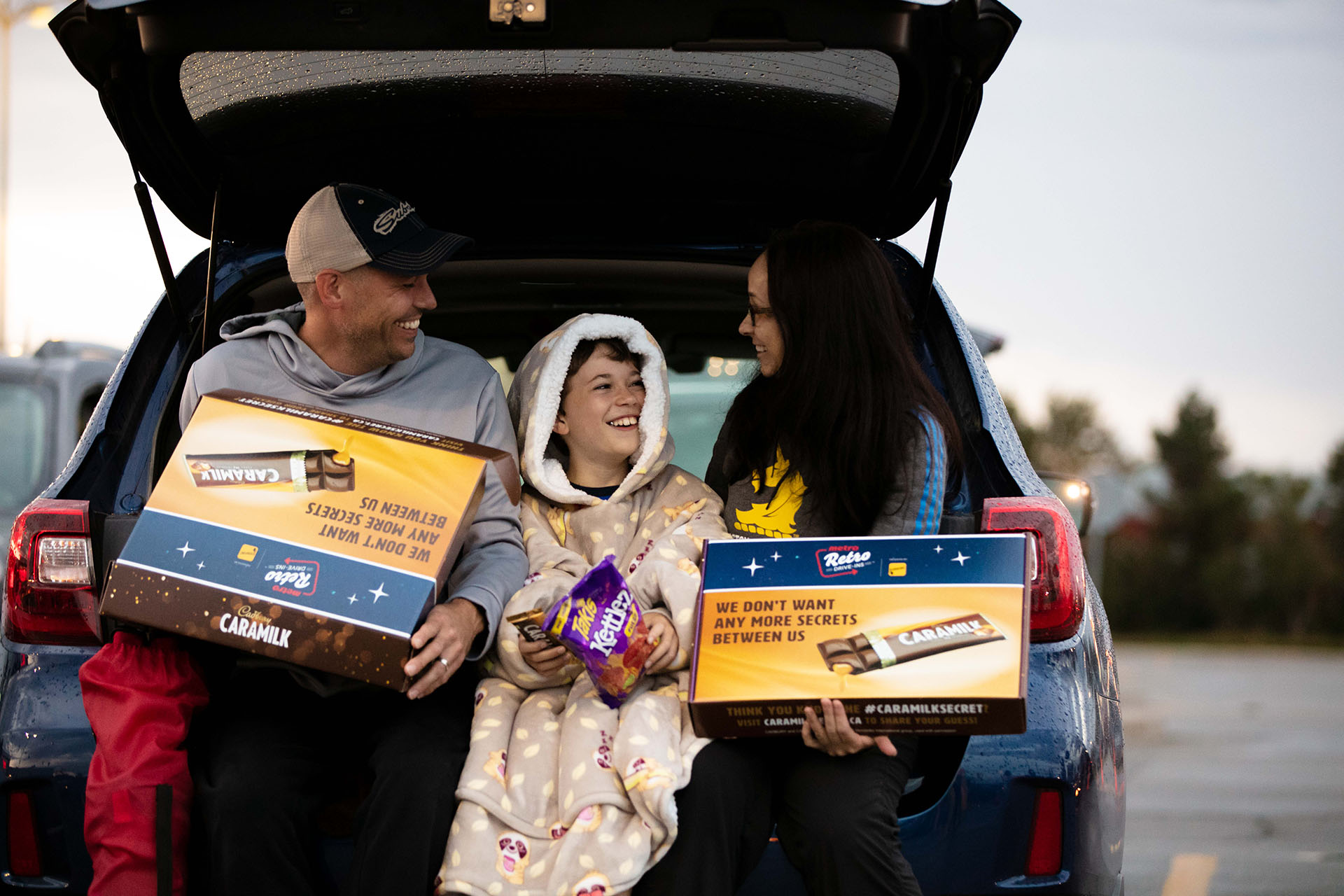 A family sitting in the back of a car holding chocolate samples