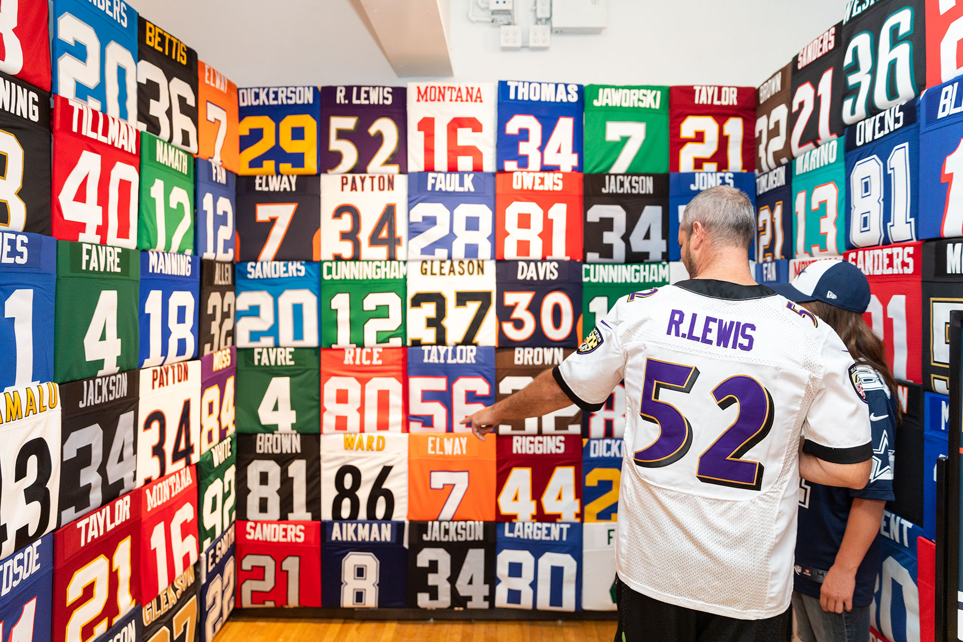 Fans looking at a display wall of NFL jerseys