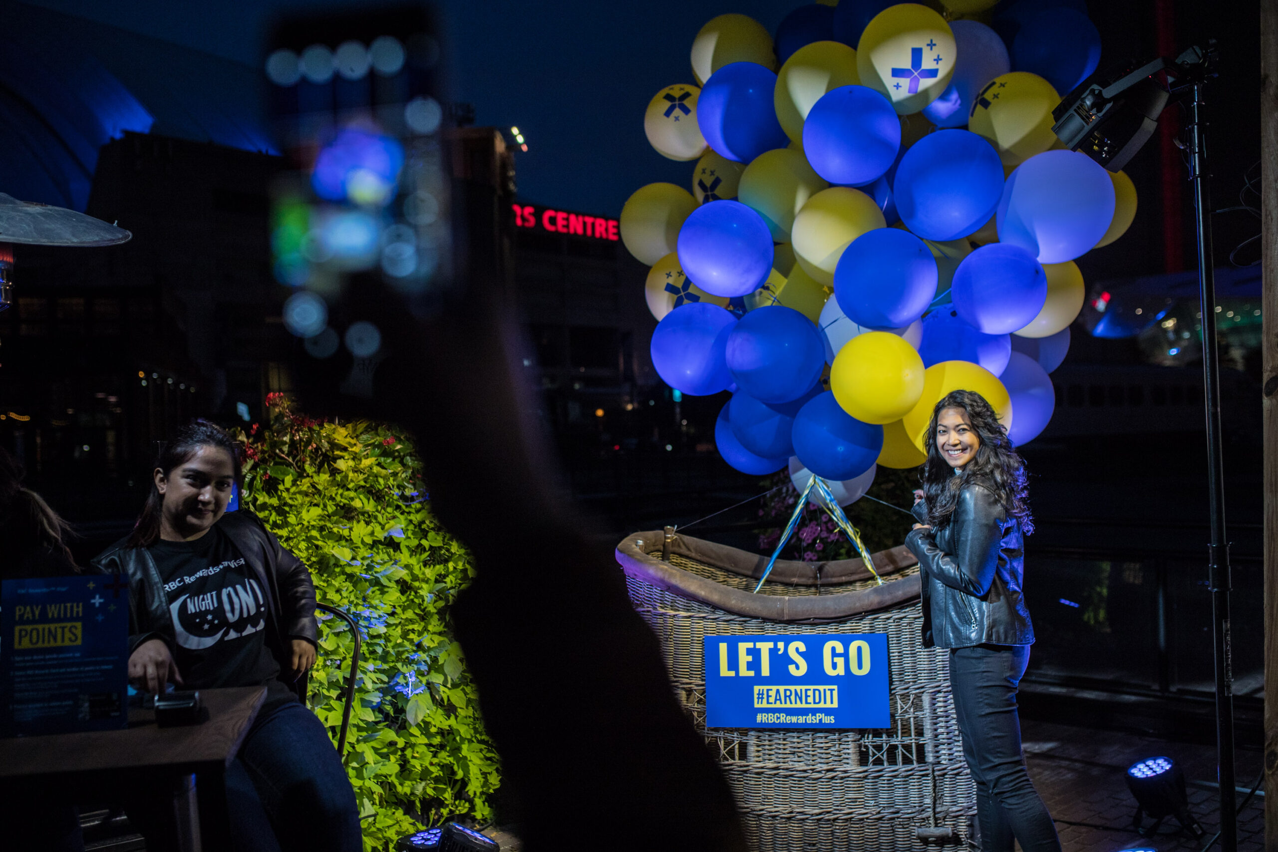 a young woman standing in front of a hot air balloon basket with blue and yellow balloons