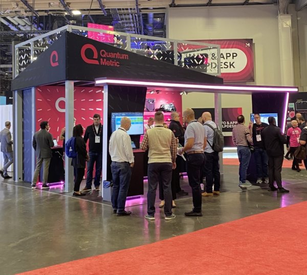 A group of people standing outside a Quantum Metric conference booth