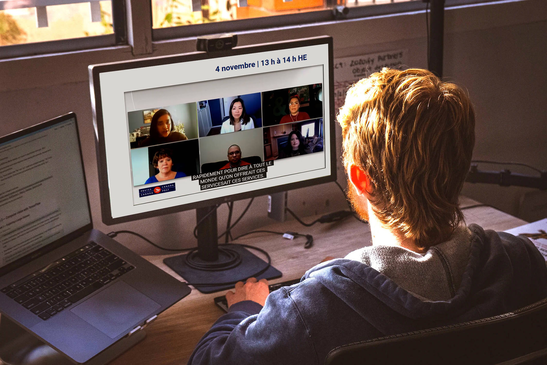 A man sitting in front of a computer screen watching a virtual meeting