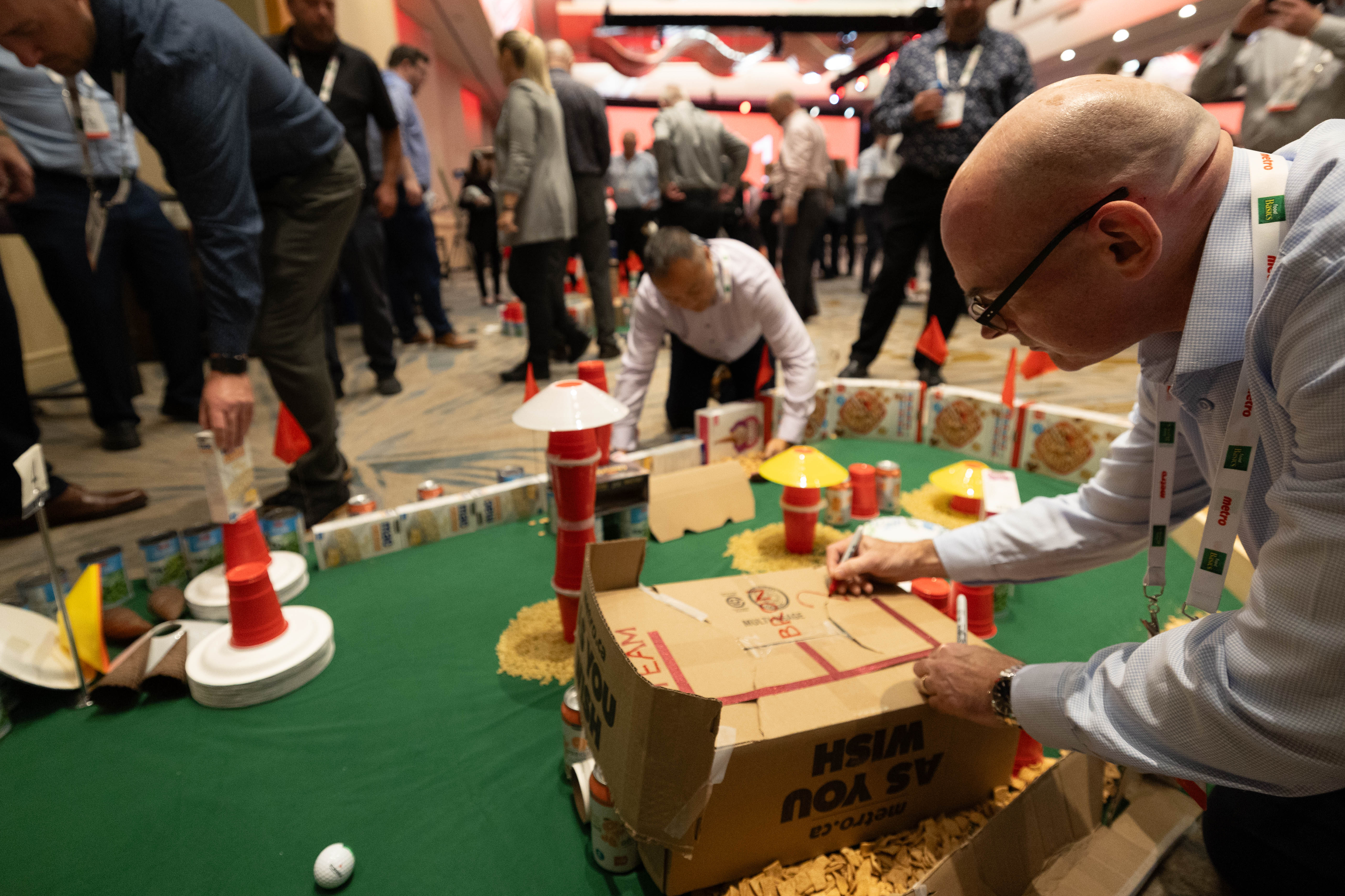 Man building mini golf putt hole with cardboard box